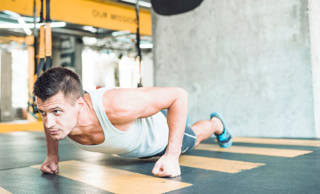 Young man doing push-ups in a fitness club